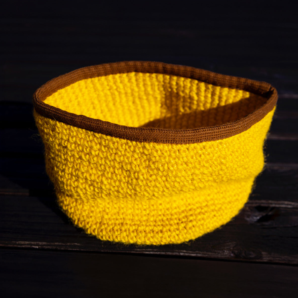 Cesto porta giochi per gatto di Orme Differenti, lavorato a uncinetto in fibre 100% naturali, colore giallo e bordo marrone rinforzato.